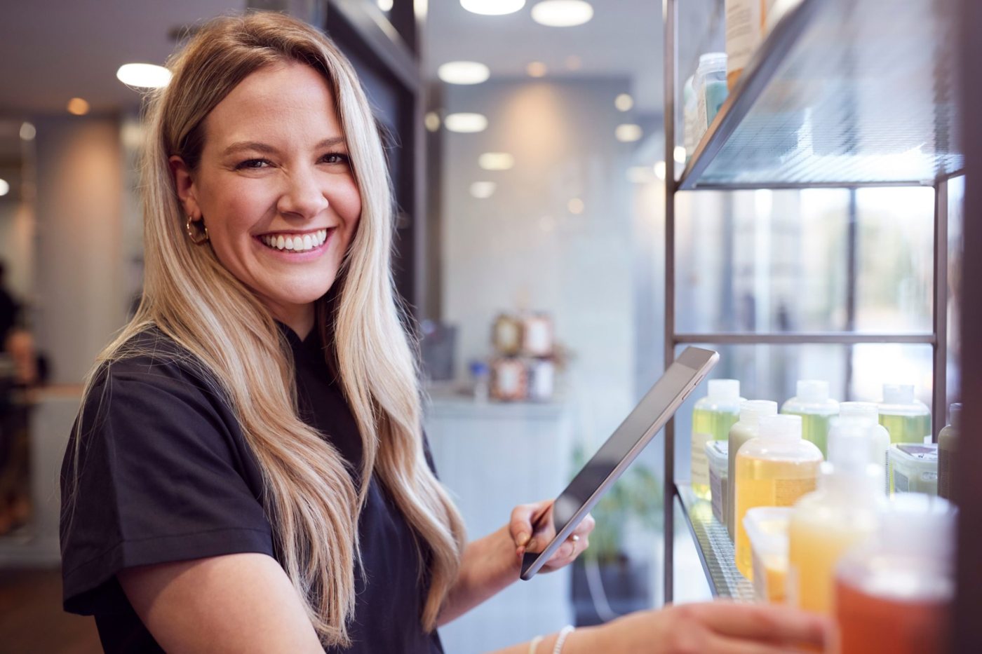 A smiling salon owner holding a tablet