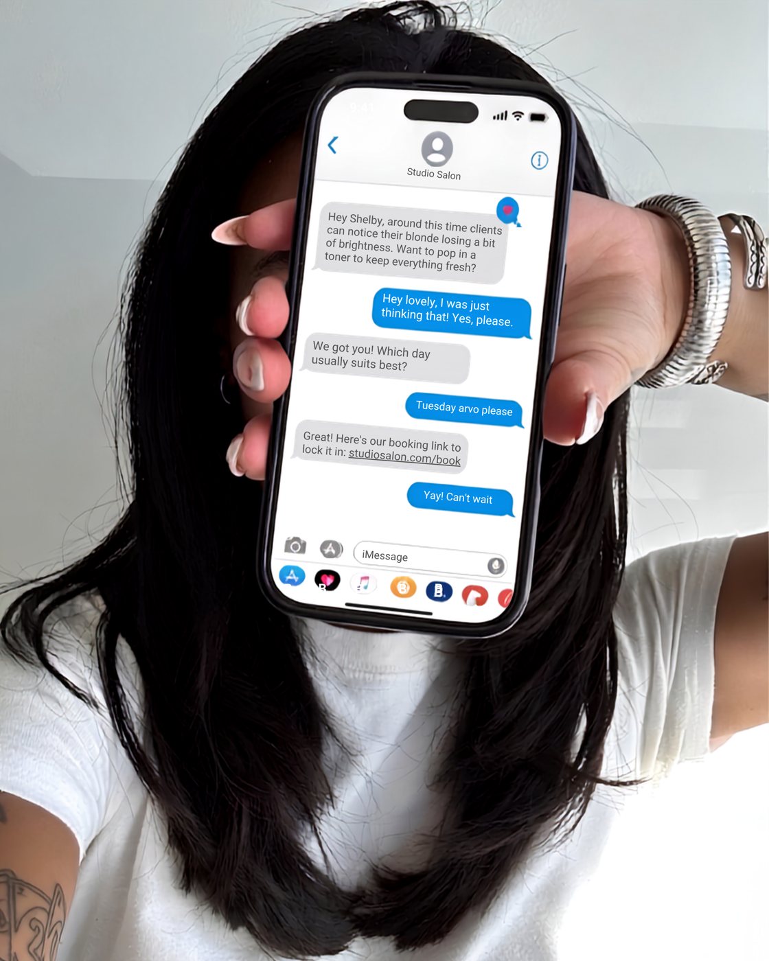 A client holding up her phone showing a text conversation with her salon